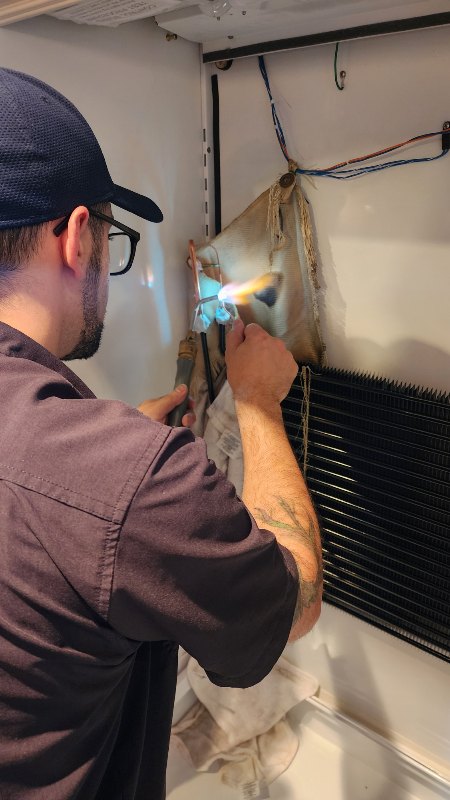 Someone repairing an appliance and holding a torch by Dynamic Appliance Repair