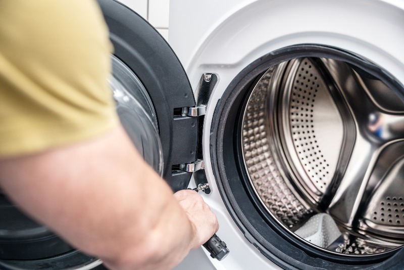 Technician repairing a front-load washing machine in a laundry room in Arizona