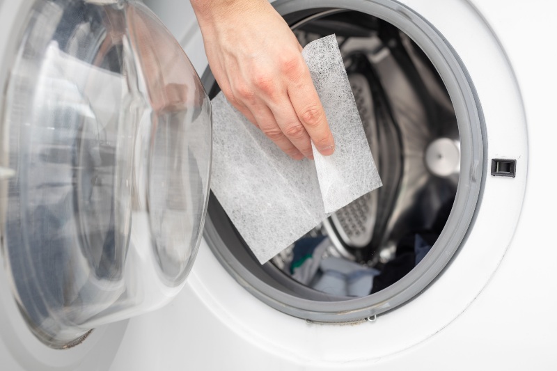 Placing dryer sheet into front-load clothes dryer for improved drying performance in Fountain Hills, AZ