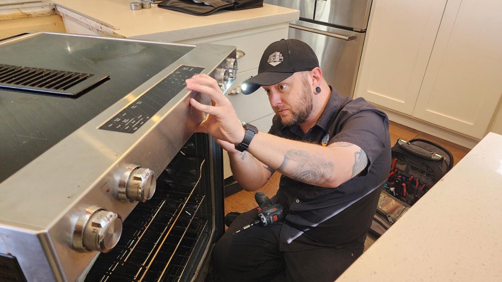 Technician inspecting a built-in oven control panel during repair in Gilbert & Fountain Hills, AZ<br />
