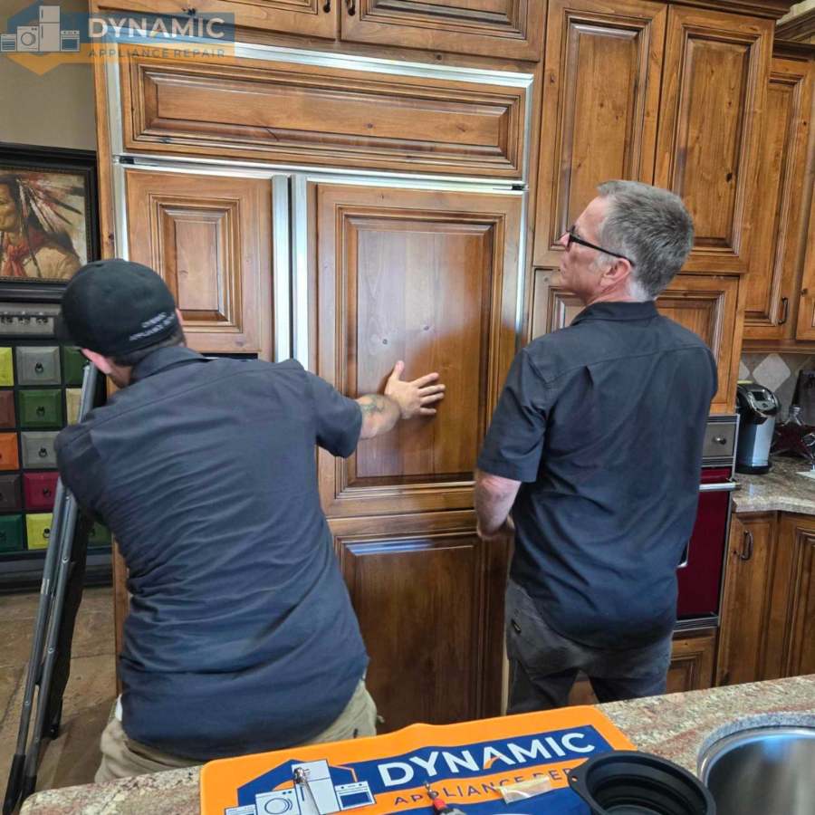 Technicians servicing a built-in refrigerator in a home kitchen in Gilbert & Fountain Hills, AZ<br />
