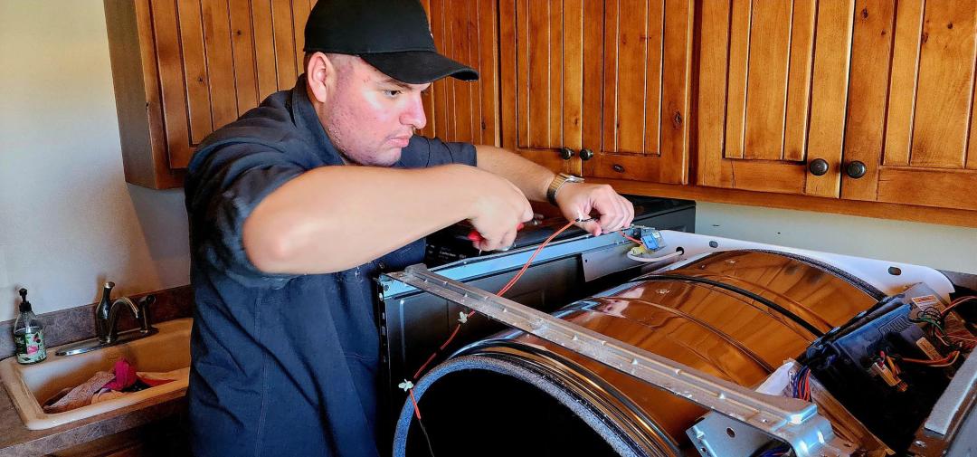 technician-repairing-household-washer Technician repairing a household washer in a kitchen in Gilbert & Fountain Hills, AZ<br />